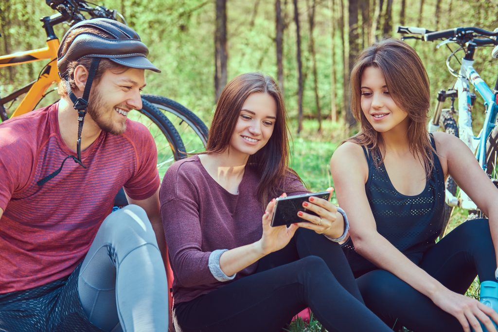group of young friends hiking through the forest with bikes on a