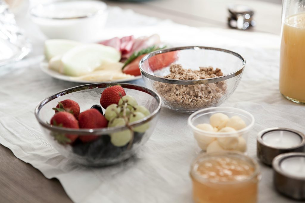 A delicious and nutritious breakfast spread featuring fresh fruits, granola, and juice on a dining table.
